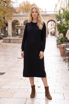 Nuggles® Oakley Hoodie Dress in Black, full-length front view on a stone plaza with brown ankle boots