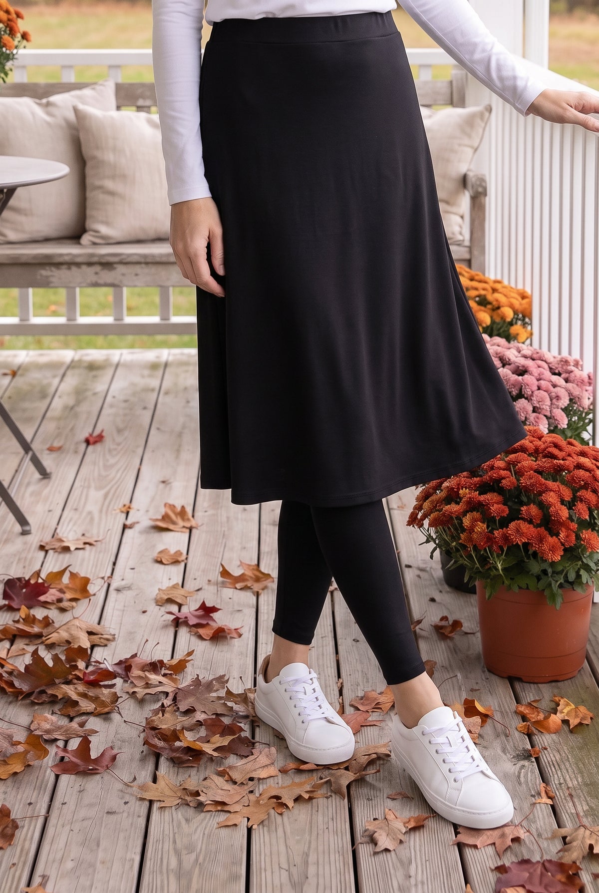 Nuggles® Tilly Sport Skirt in Black, waist-down front view mid-step with one hand resting on the porch railing