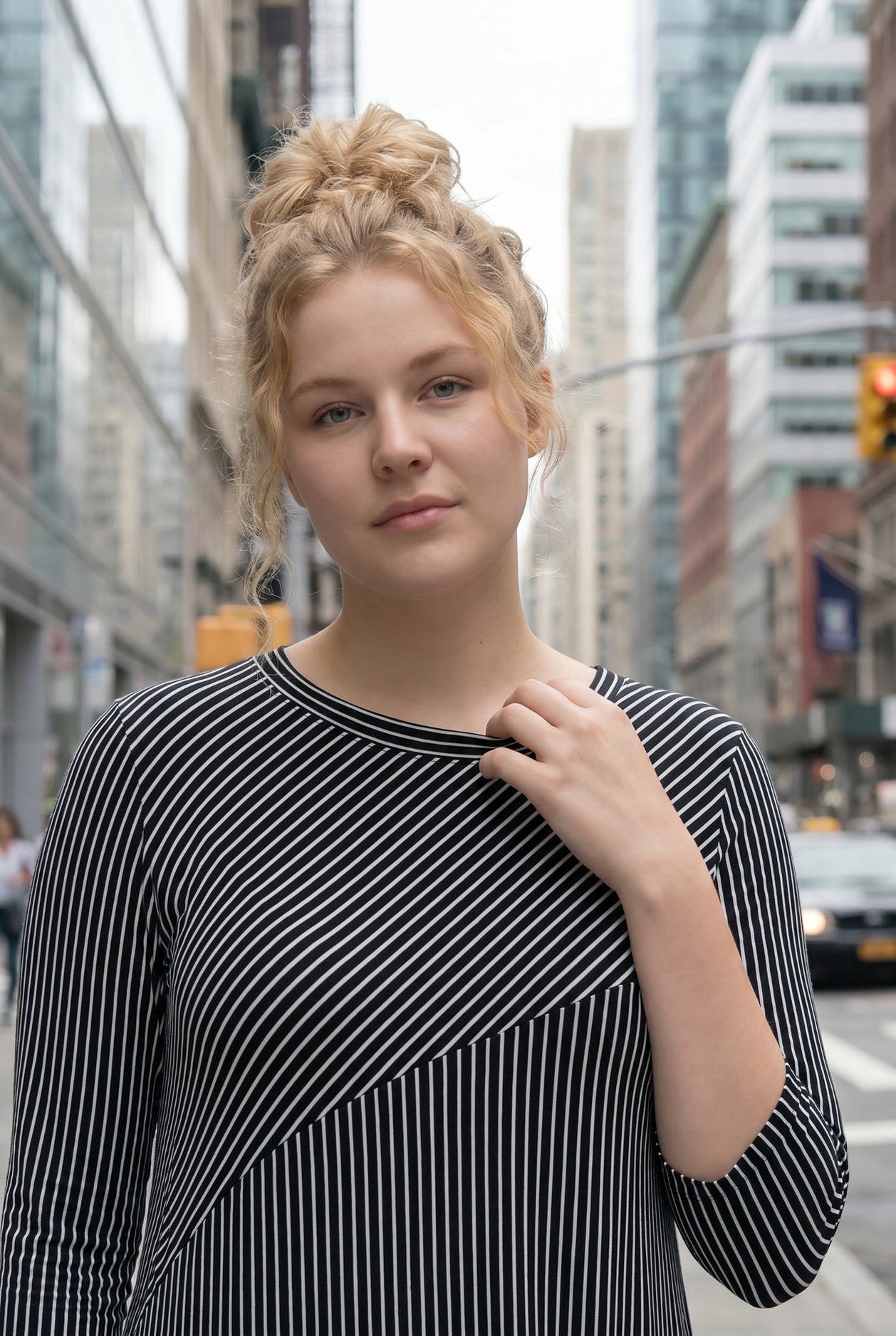 Woman in a black and white striped dress standing on a city street.