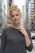 Woman in a black and white striped dress standing on a city street.