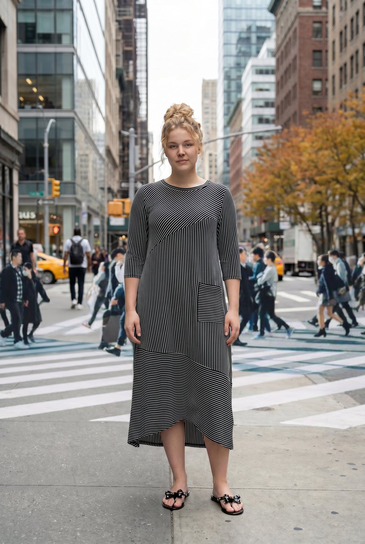Woman in a black and white striped dress standing on a city street.