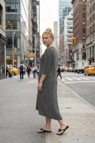 Woman in a black and white striped dress standing on a city street.