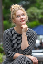 Woman in a striped dress sitting outdoors with trees in the background