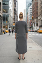 Woman in a black and white striped dress standing on a city street.