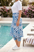 Person wearing a blue patterned skirt by a poolside