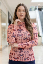A picture of a women wearing a pink, red, and blue bow print mesh tee. 