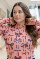 A picture of a women wearing a pink, red, and blue bow print mesh tee. 