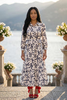 A picture of a young women wearing the Leila Dress in a bow print with a soft ivory base. 