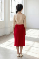 Girl wearing Nuggles® Modest Midi Skirt in Brick Red with a nude essential 3/4 tee in a sun light loft