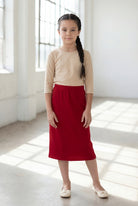 Girl wearing Nuggles® Modest Midi Skirt in Brick Red with a nude essential 3/4 tee in a sun light loft