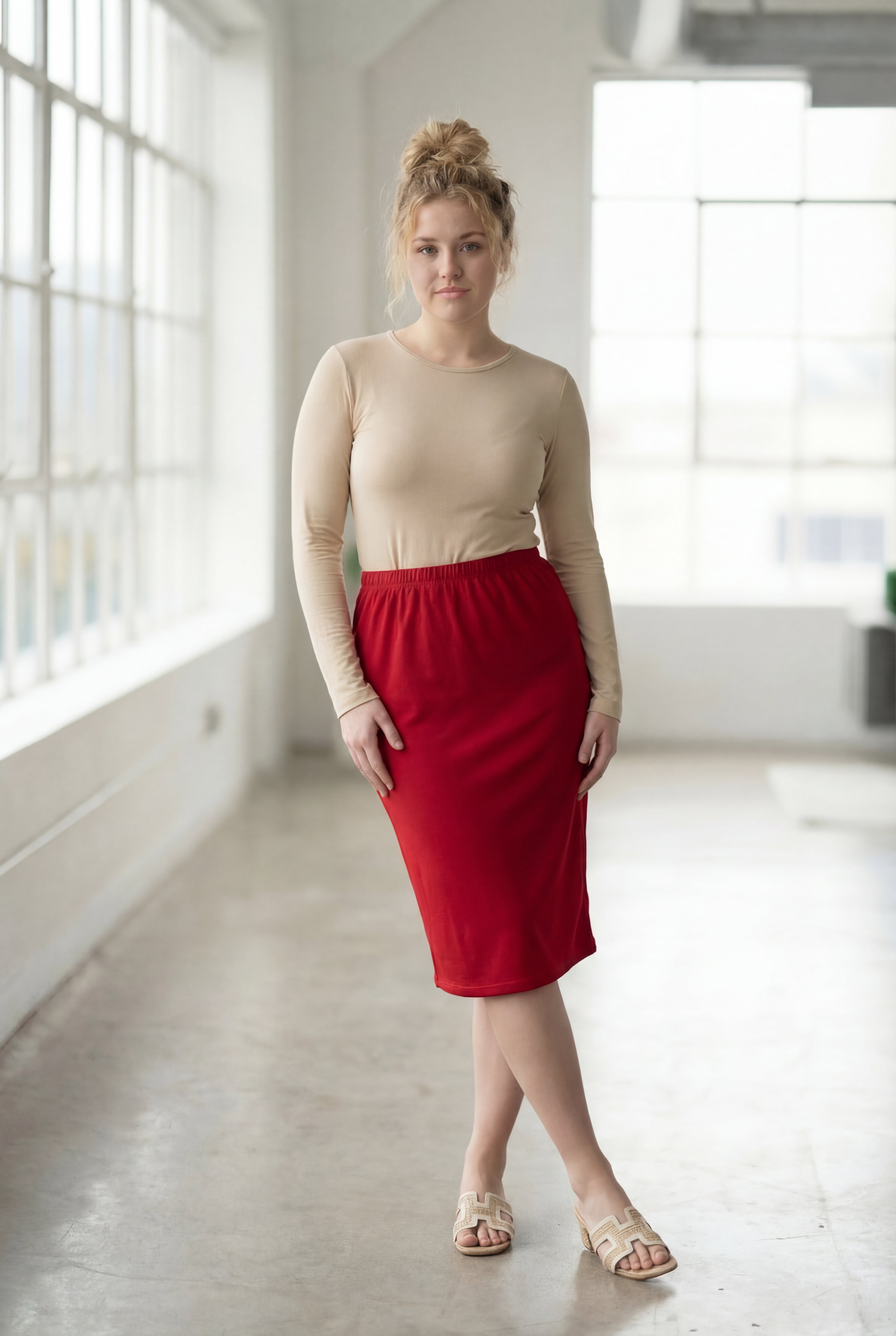 Women wearing a brick red classic 27" midi length skirt with a beige shirt in a sunlight loft.