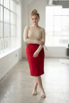 Women wearing a brick red classic 27" midi length skirt with a beige shirt in a sunlight loft.