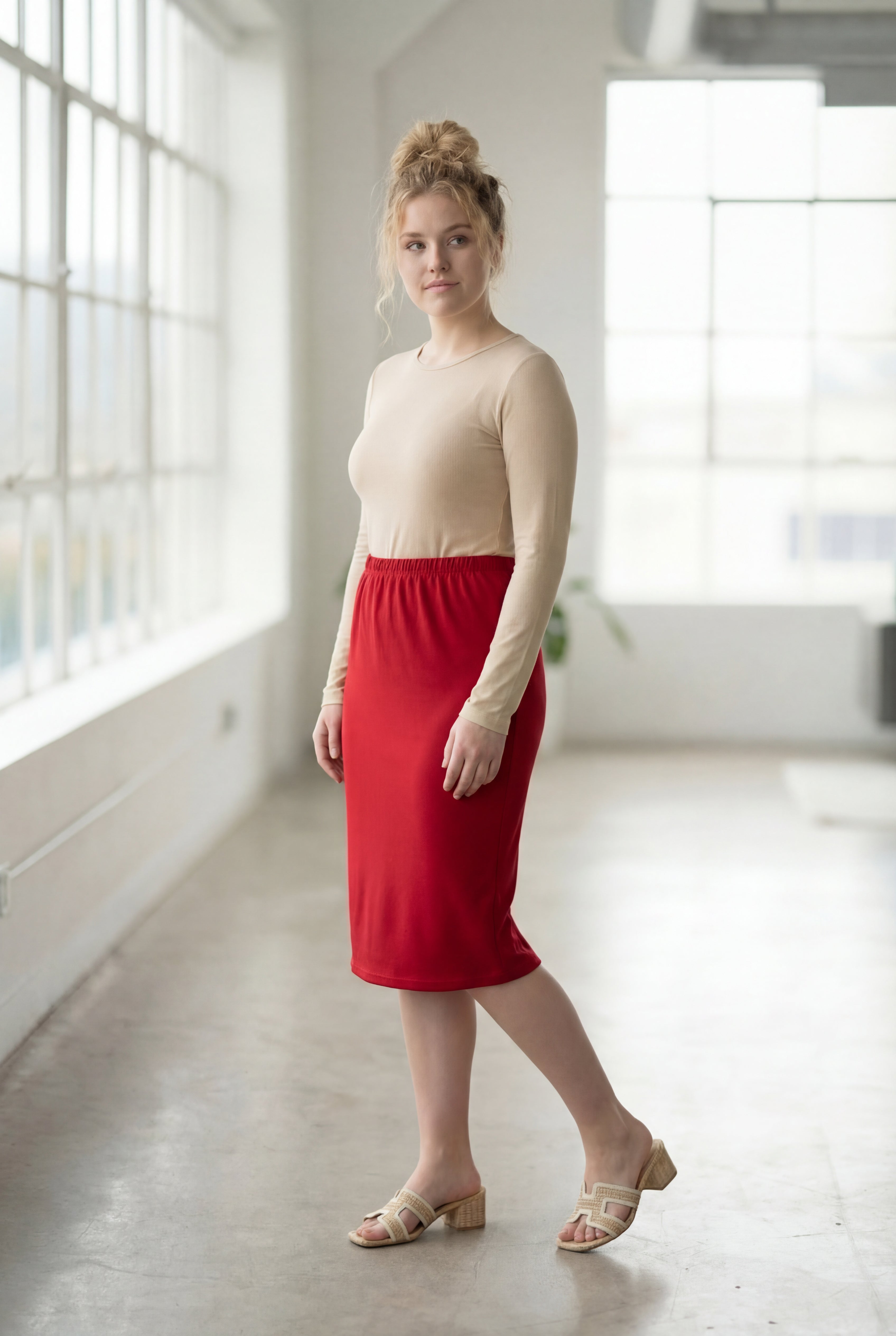 Women wearing a brick red classic 27" midi length skirt with a beige shirt in a sunlight loft.