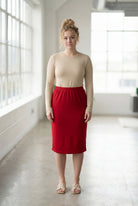 Women wearing a brick red classic 27" midi length skirt with a beige shirt in a sunlight loft.