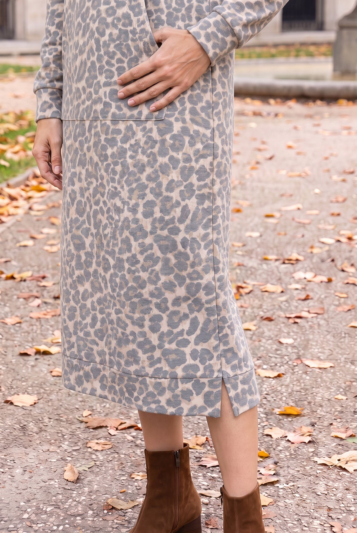 Nuggles® Hoodie Dress in Classic Leopard, close-up of the banded hem and side slit above brown boots