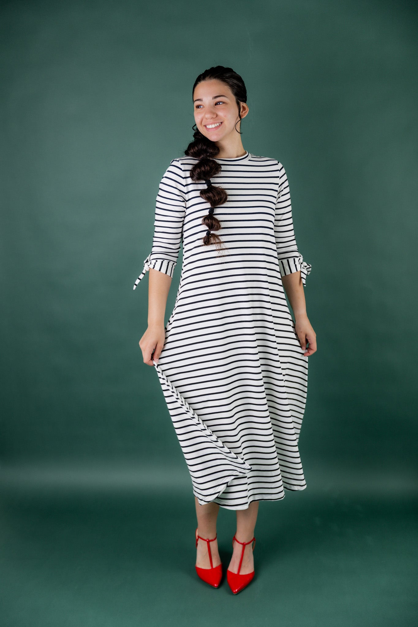 Model wearing the Nuggles® Gracie Dress, a modest A-line midi dress with ¾ sleeves and tie accents, made from soft knit fabric.