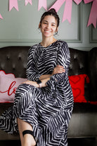 Model wearing Nuggles® Hazel Dress in Zebra Swirl black and white print with bow sleeves.