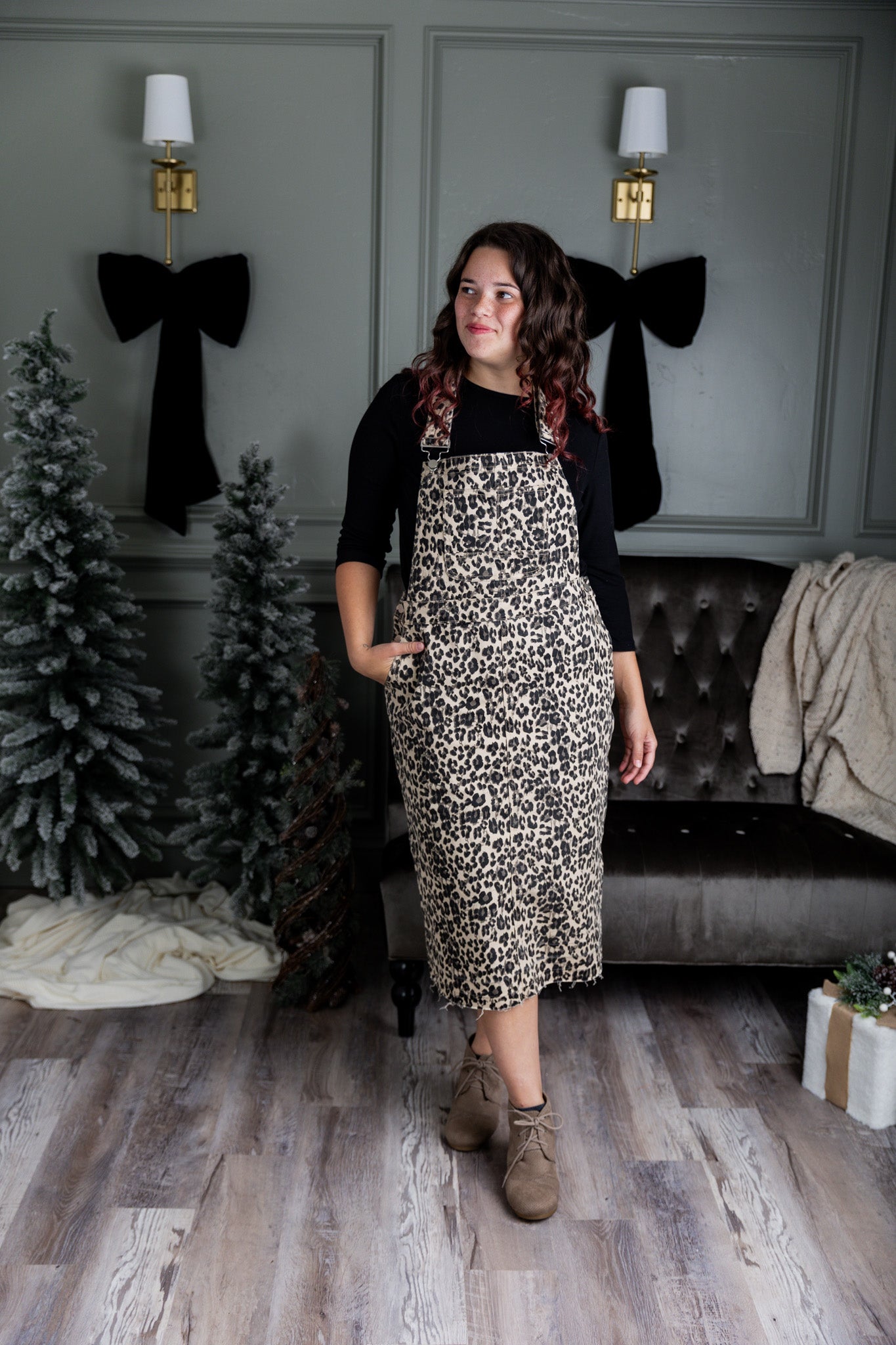Model wearing a 'NUGGLES® modest leopard denim overall dress with front pocket and raw hem.

