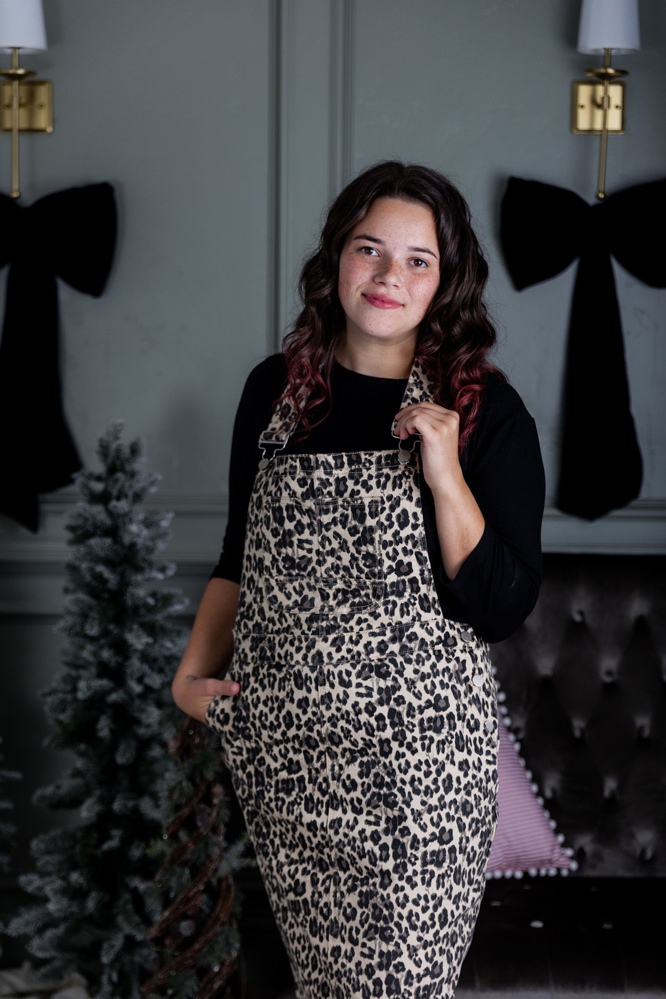 Model wearing a 'NUGGLES® modest leopard denim overall dress with front pocket and raw hem.