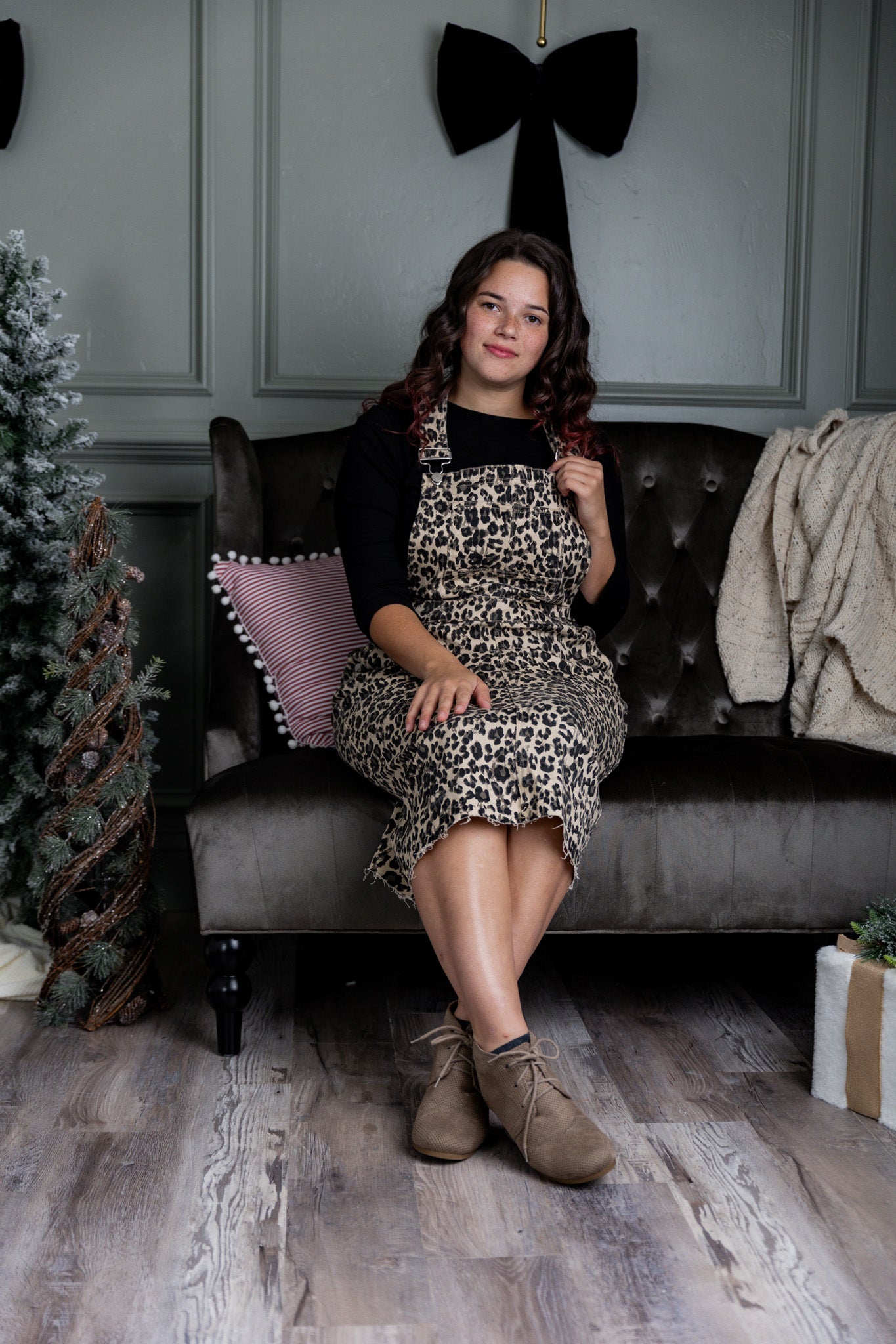 Model wearing a 'NUGGLES® modest leopard denim overall dress with front pocket and raw hem.