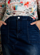 Nuggles® denim midi skirt with soft stretch fabric, wide elastic waistband, modest length, and functional pockets. Available in 27", 31", and 34" lengths.