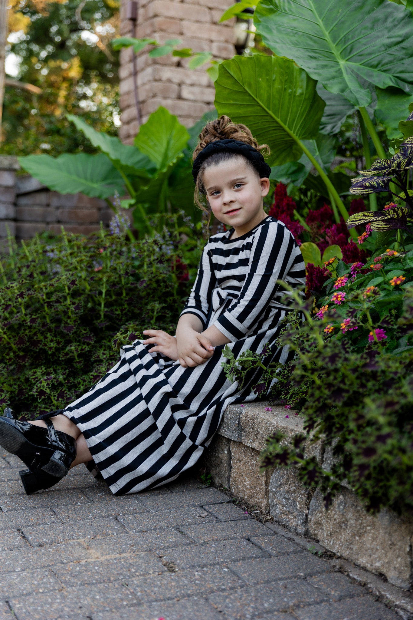 Young girl wearing the Nuggles® Girls Adelia Dress — a modest striped maxi dress with bow tie waist.