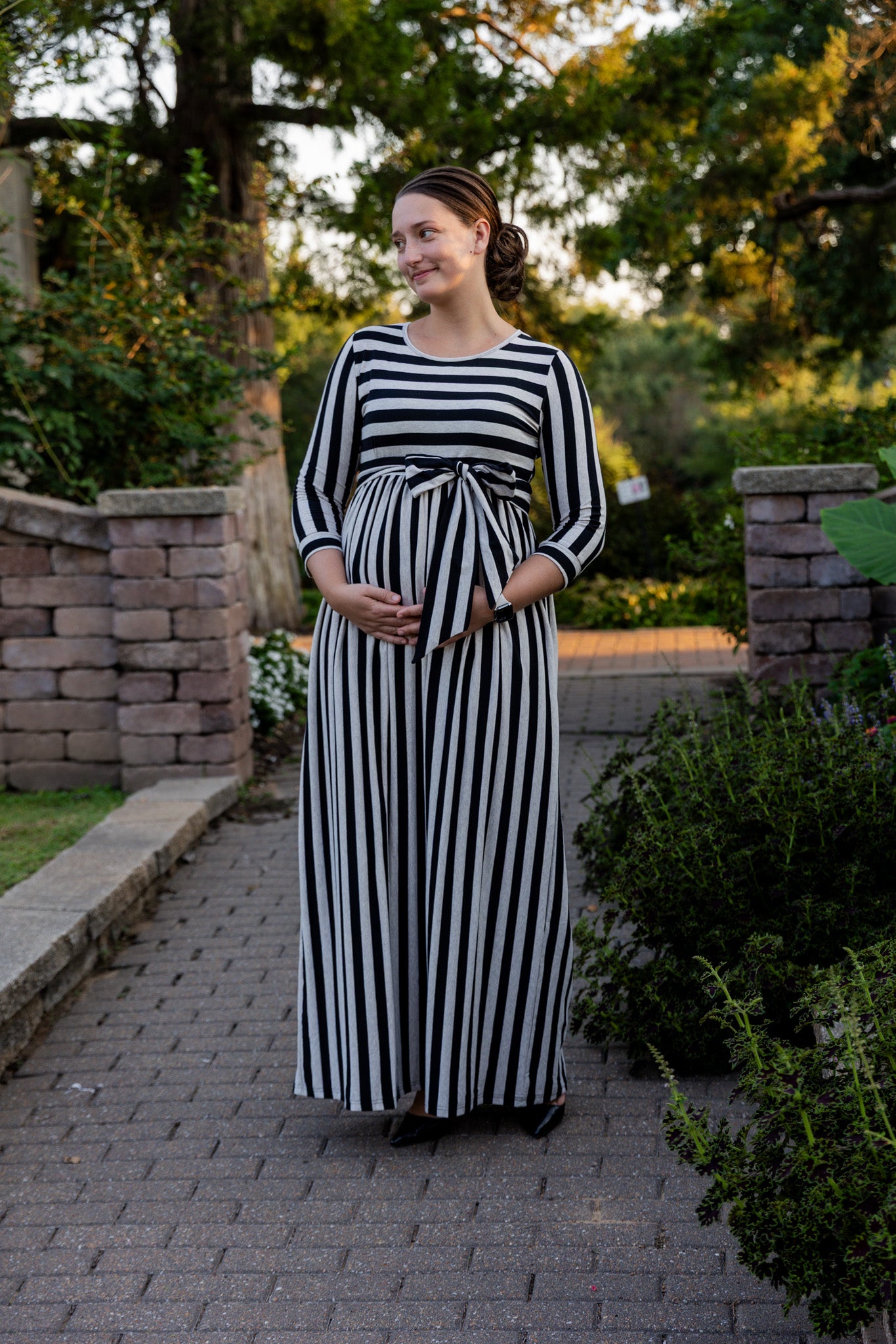 Model wearing the Nuggles® Adelia Dress, a modest striped maxi dress with waist tie and ¾ sleeves.