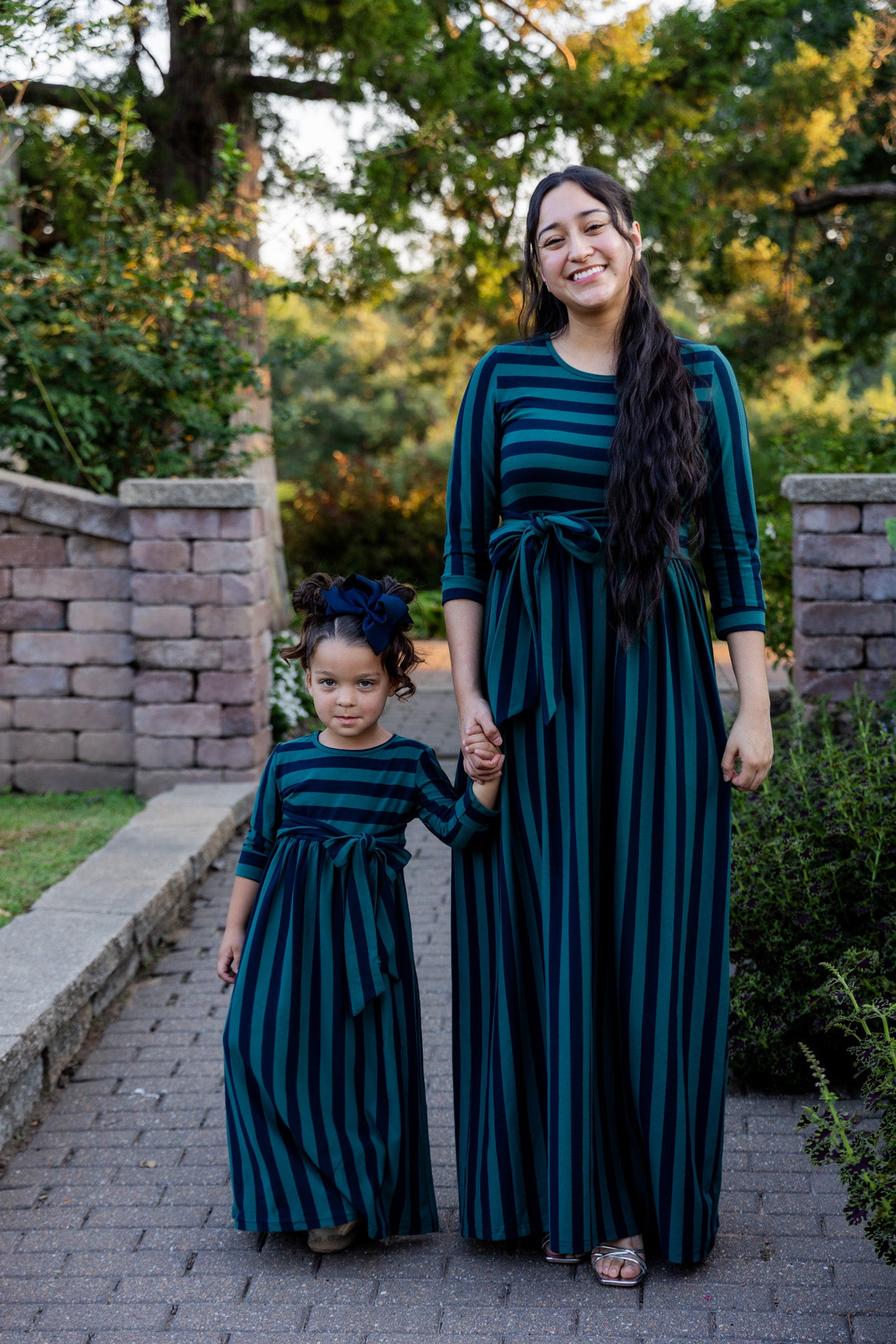 Model wearing the Nuggles® Adelia Dress, a modest striped maxi dress with waist tie and ¾ sleeves.