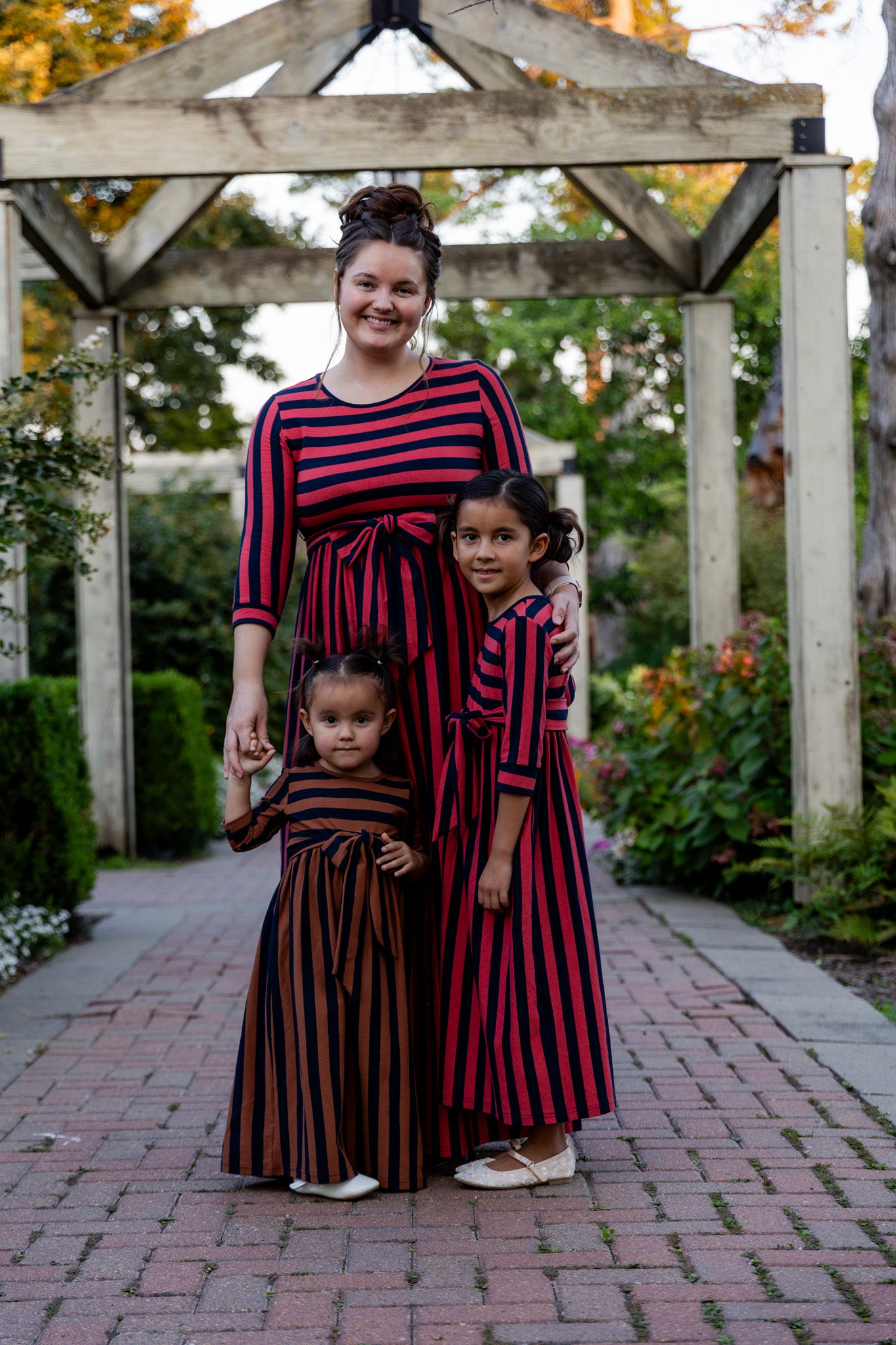 Model wearing the Nuggles® Adelia Dress, a modest striped maxi dress with waist tie and ¾ sleeves.