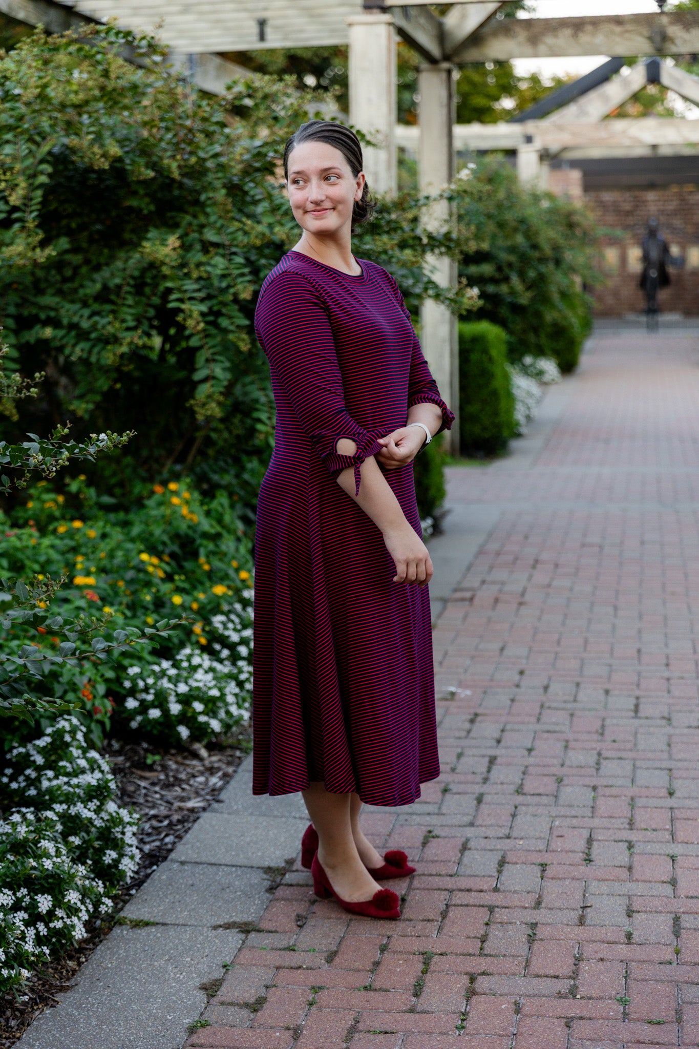 Model wearing the Nuggles® Gracie Dress, a modest A-line midi dress with ¾ sleeves and tie accents, made from soft knit fabric.