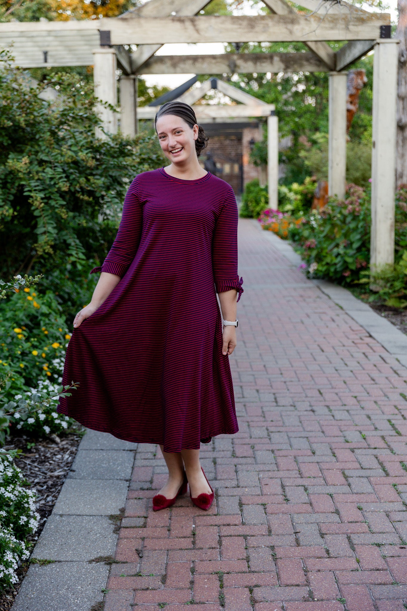 Model wearing the Nuggles® Gracie Dress, a modest A-line midi dress with ¾ sleeves and tie accents, made from soft knit fabric.