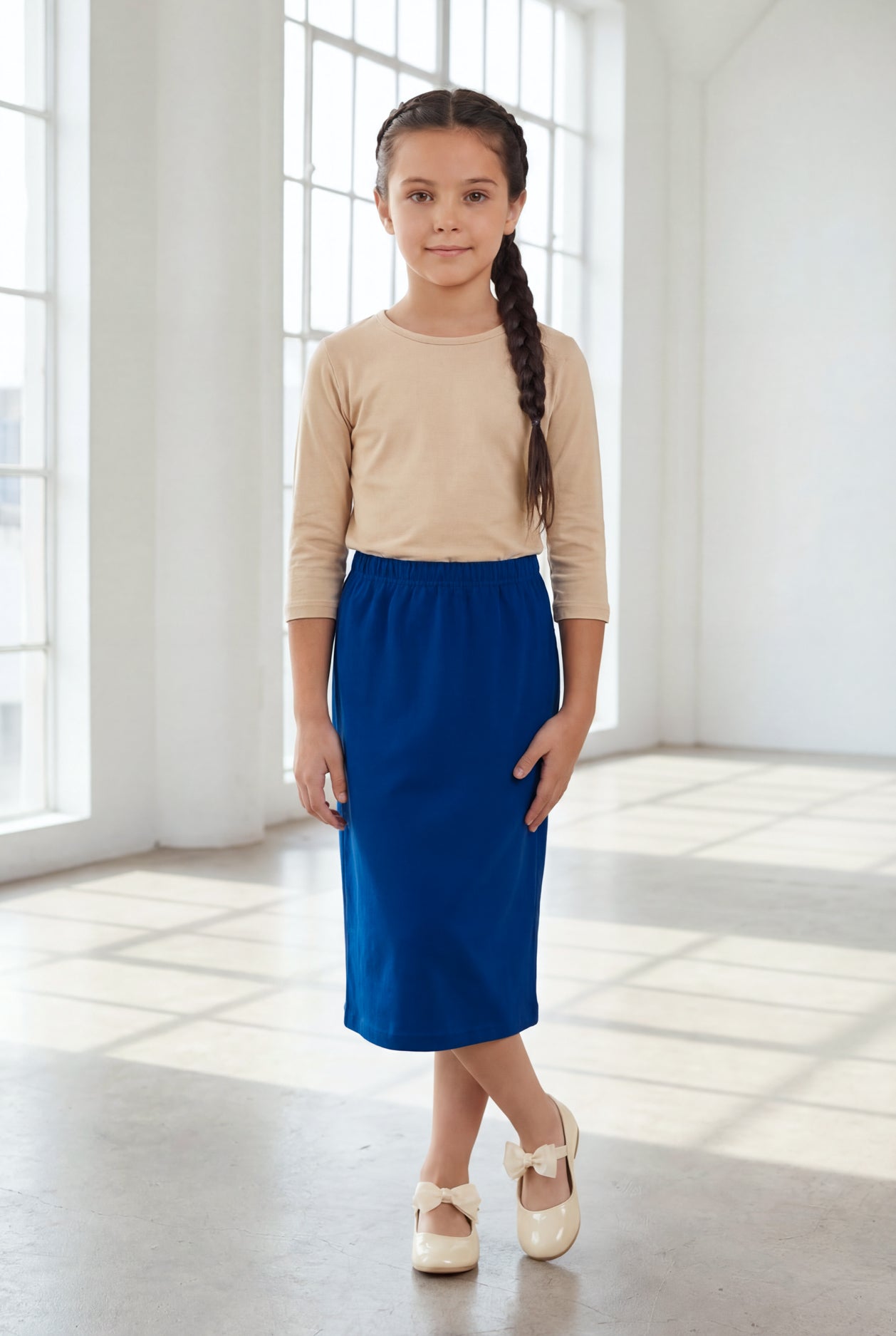 Young girl wearing a modest midi length skirt in dark royal with a beige colored 3/4 length sleeve shirt. 
