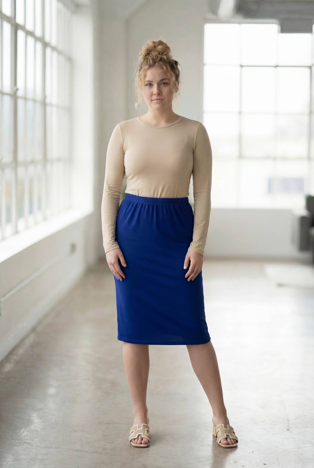 Women wearing a brick dark royal classic 27" midi length skirt with a beige shirt in a sunlight loft.