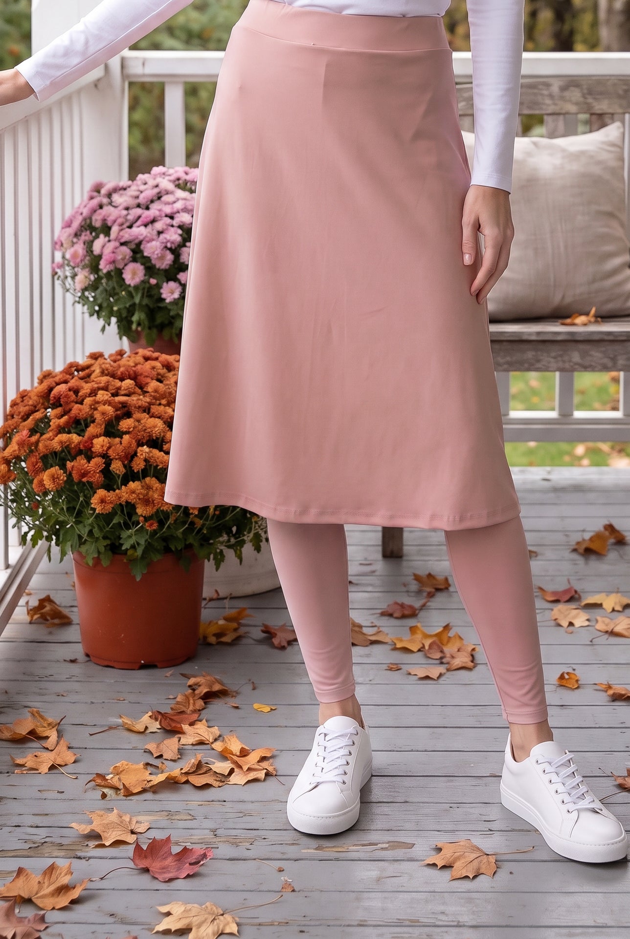 Nuggles® Tilly Sport Skirt in Dusty Pink, waist-down front view with one hand on the porch railing and matching leggings