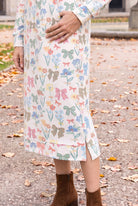 Nuggles® Hoodie Dress in Garden Party, close-up of the banded hem and side slit above brown boots