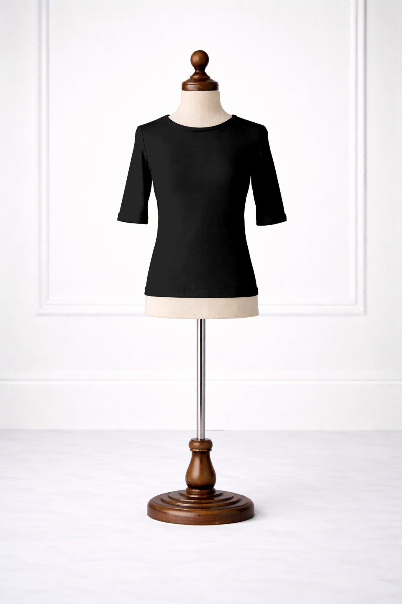 Black top on a mannequin with a wooden base against a white background