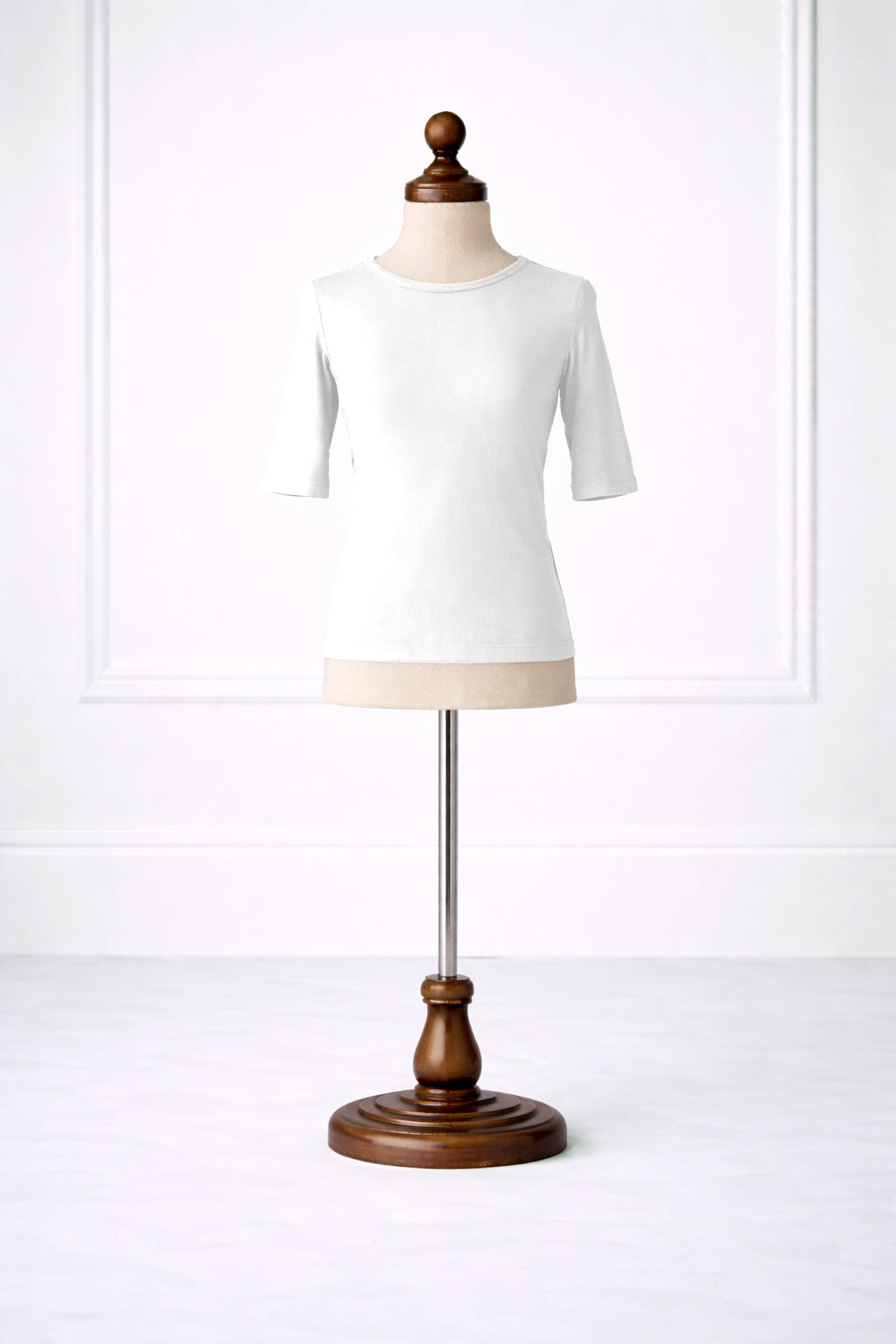 White t-shirt on a mannequin with a wooden base against a white background