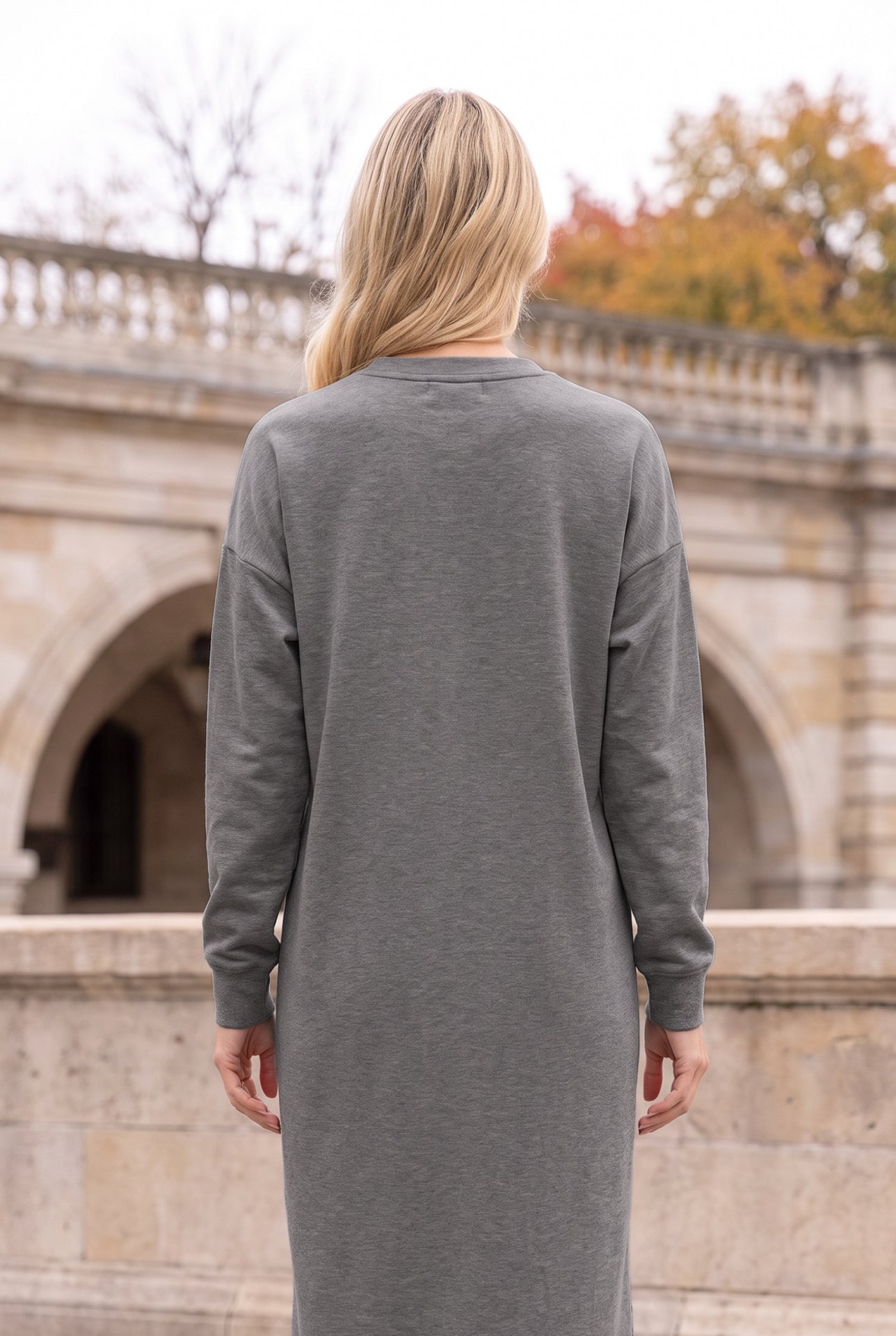 Nuggles® Oakley Hoodie Dress in Heather Gray, back view from the shoulders down in front of stone arches