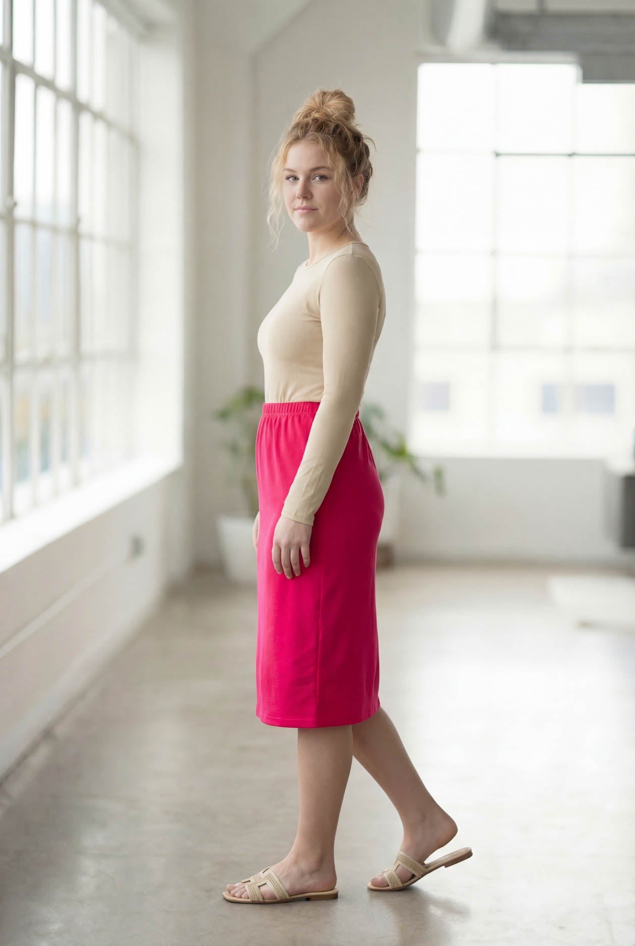 Women wearing a brick hot pink classic 27" midi length skirt with a beige shirt in a sunlight loft.