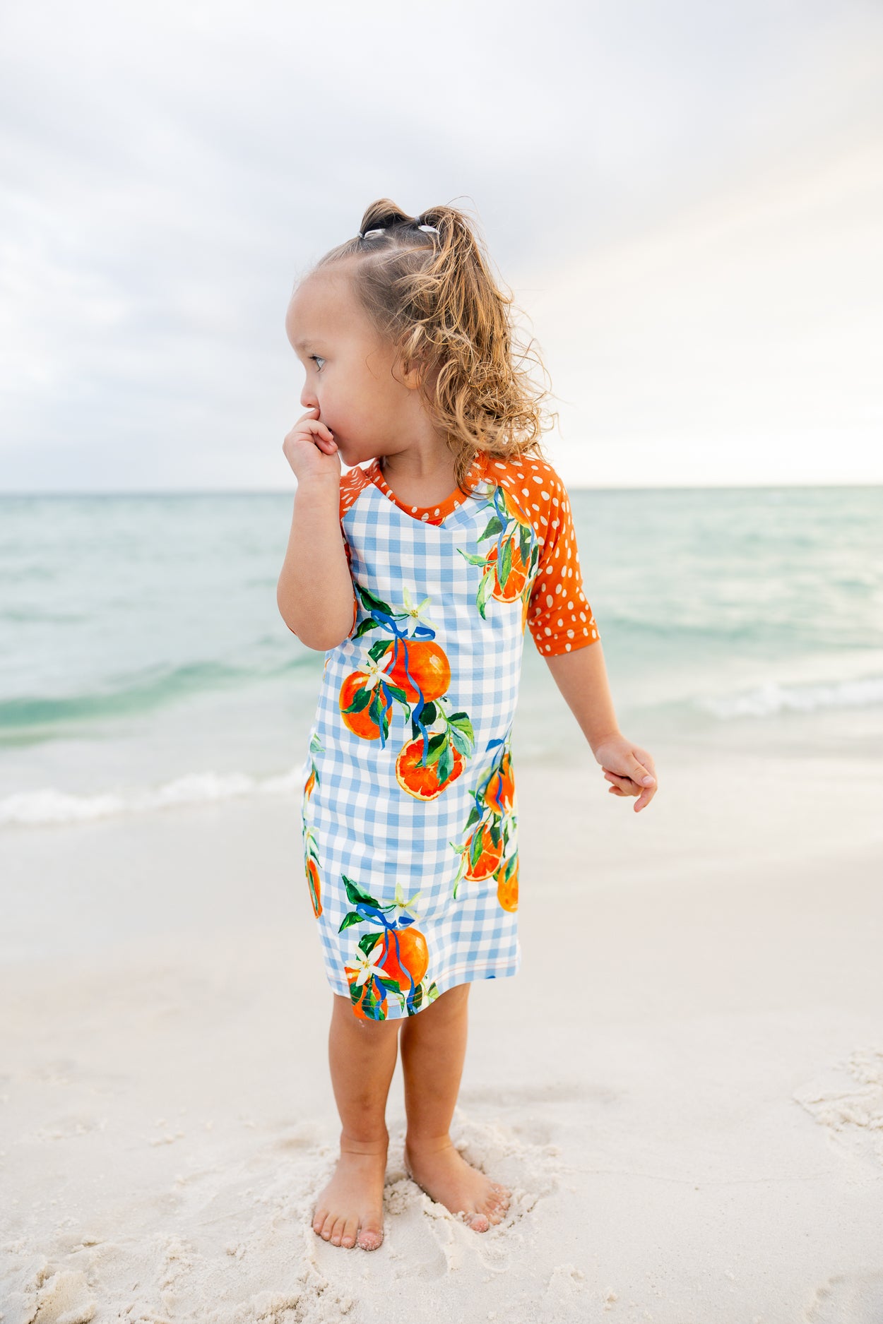 Model wearing Nuggles® Girls' Sport Swim Dress in Citrus Picnic