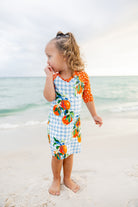 Model wearing Nuggles® Girls' Sport Swim Dress in Citrus Picnic