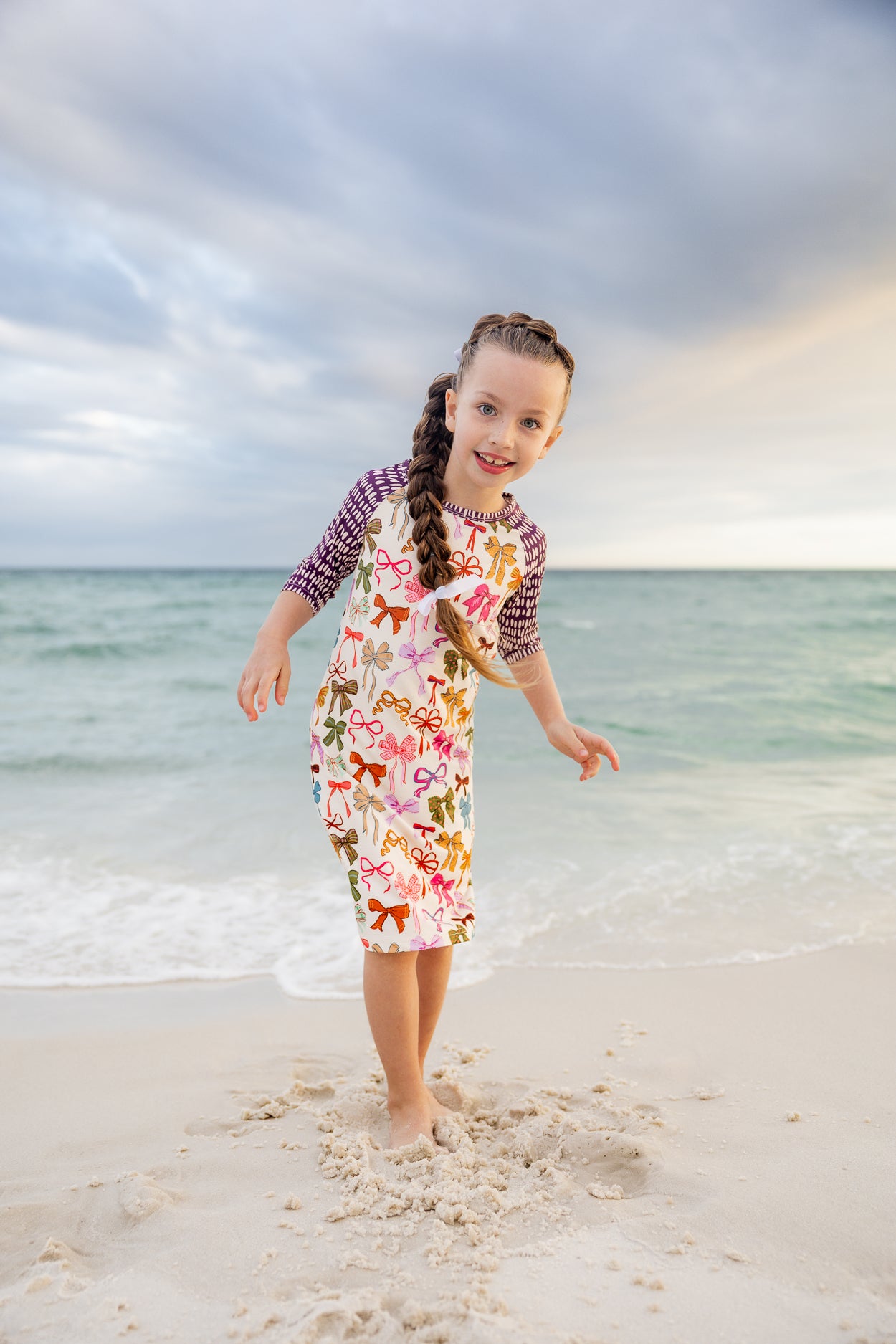 Model wearing Nuggles® Girls' Sport Swim Dress in Ribbon Scribbles