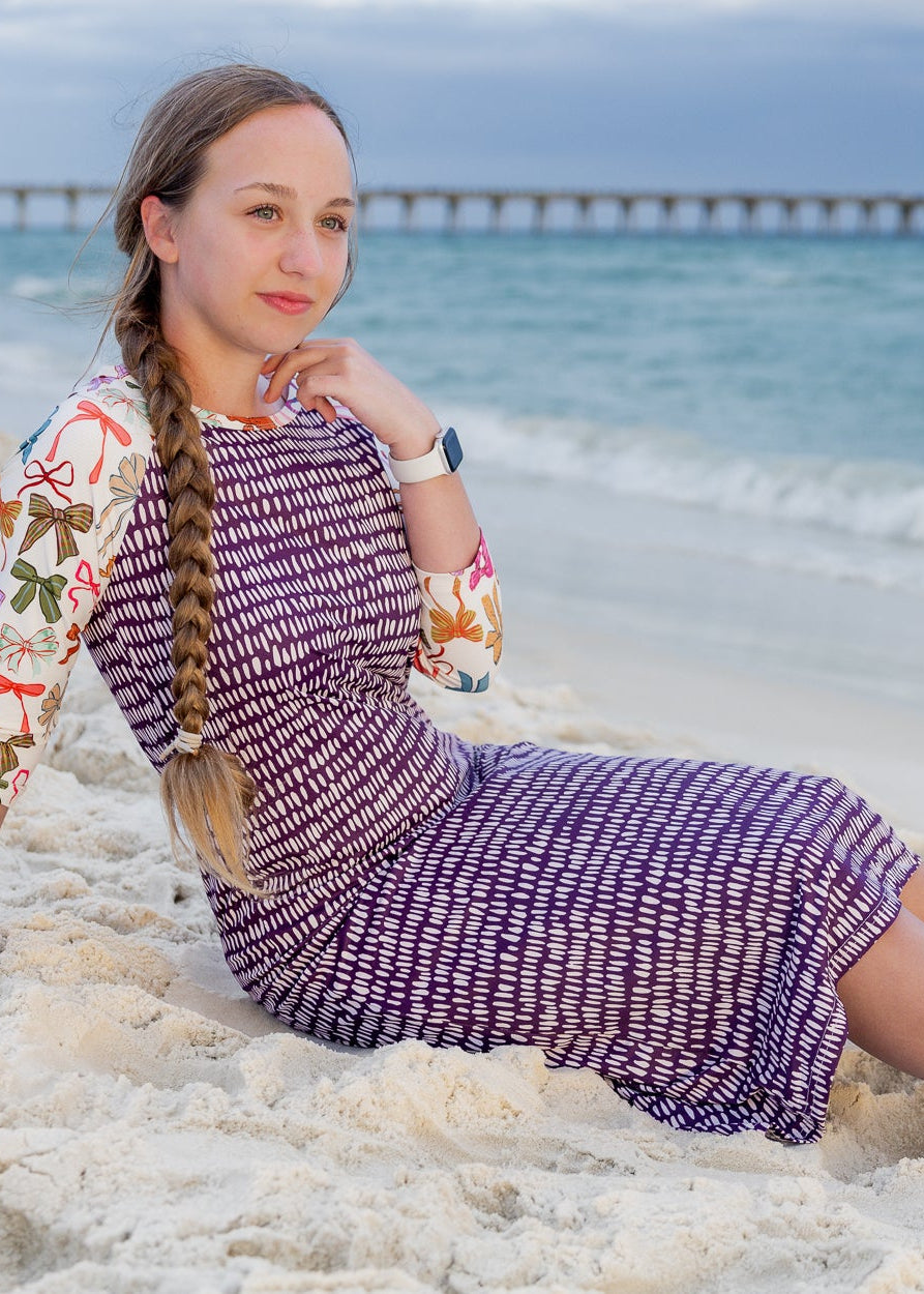 Model wearing Nuggles® Sport Swim Dress in Ribbon Scribbles