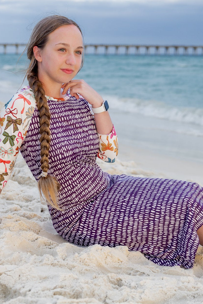 Model wearing Nuggles® Sport Swim Dress in Ribbon Scribbles