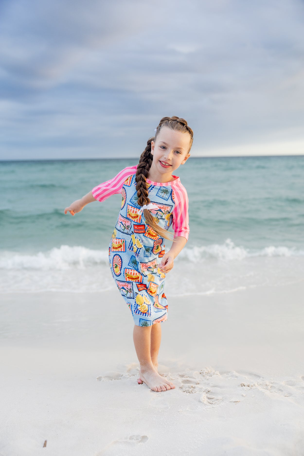 Model wearing Nuggles® Girls' Sport Swim Dress in Vacation Postcards