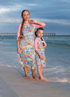 Model wearing Nuggles® Sport Swim Dress in Vacation Postcards