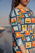 Model wearing Nuggles® Nola Sport Swim Dress in Retro Postcards