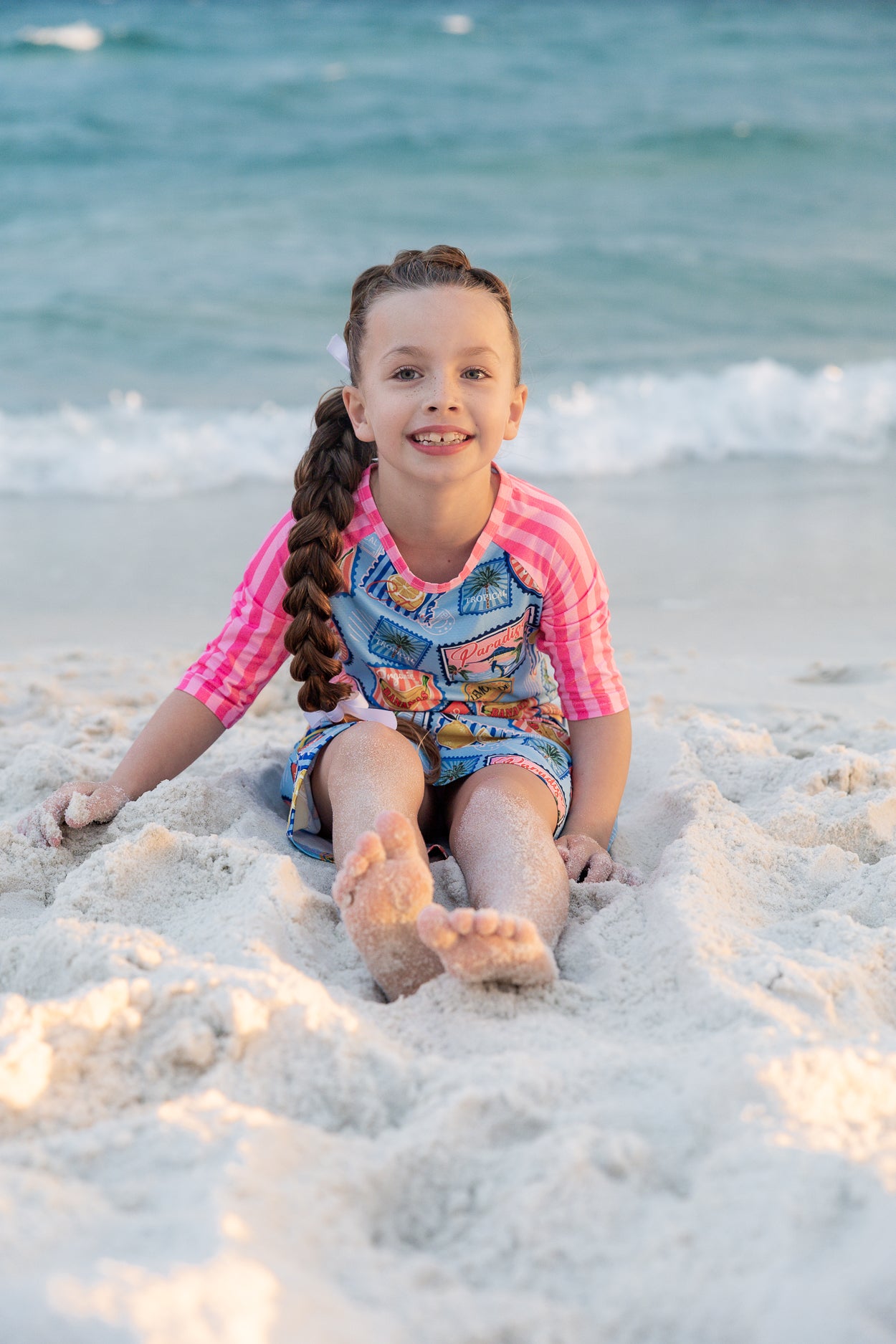 Model wearing Nuggles® Girls' Sport Swim Dress in Vacation Postcards