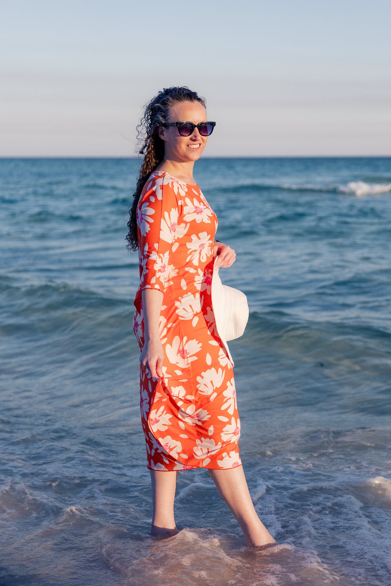 Model wearing Nuggles® Carlie Swim Dress in Sunset Hibiscus