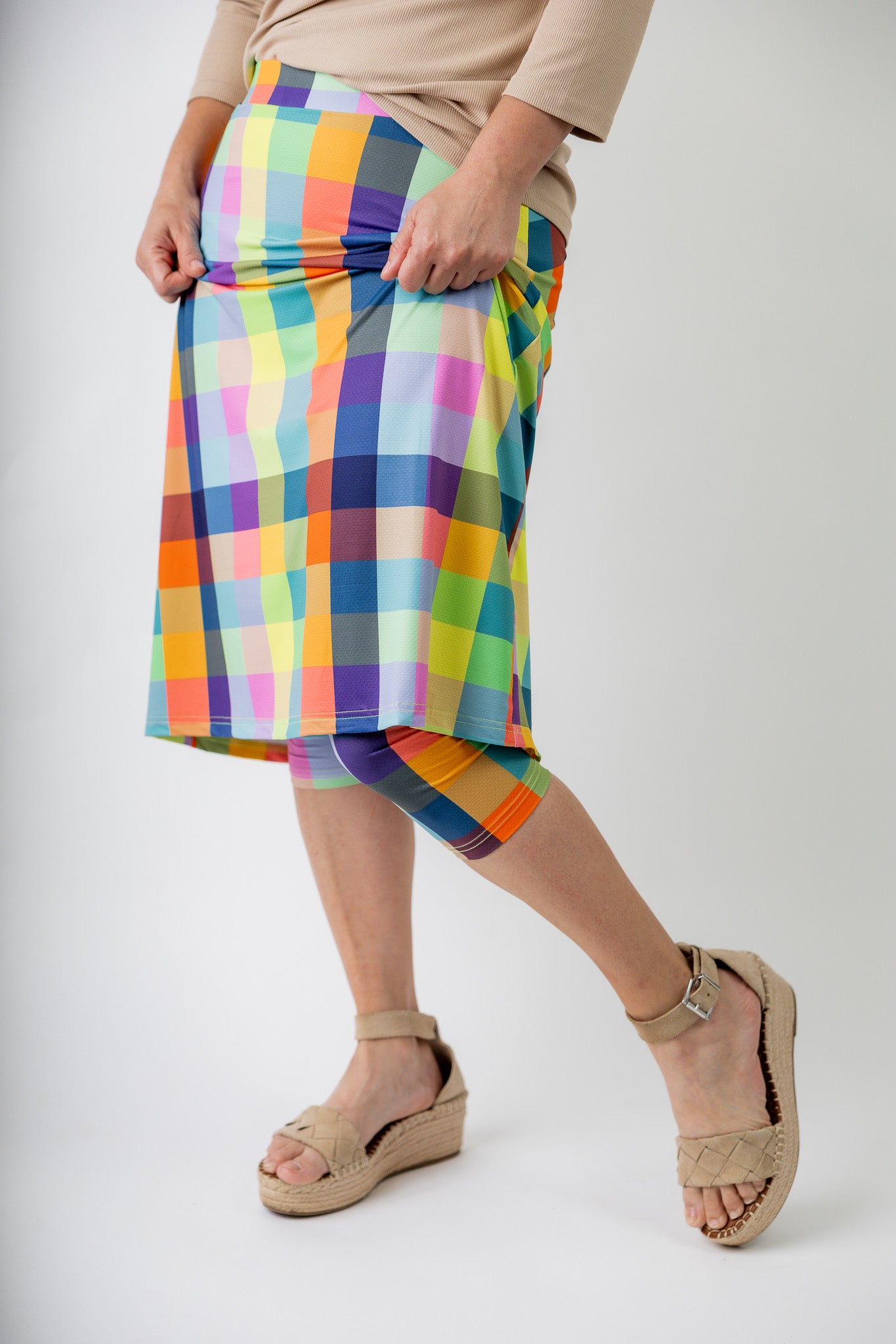 Model wearing Nuggles® Jaxon Plaid 27-inch All Sport Skirt with built-in leggings, featuring vibrant multicolor plaid pattern. Modest athletic skirt for women, designed for activewear and everyday comfort.